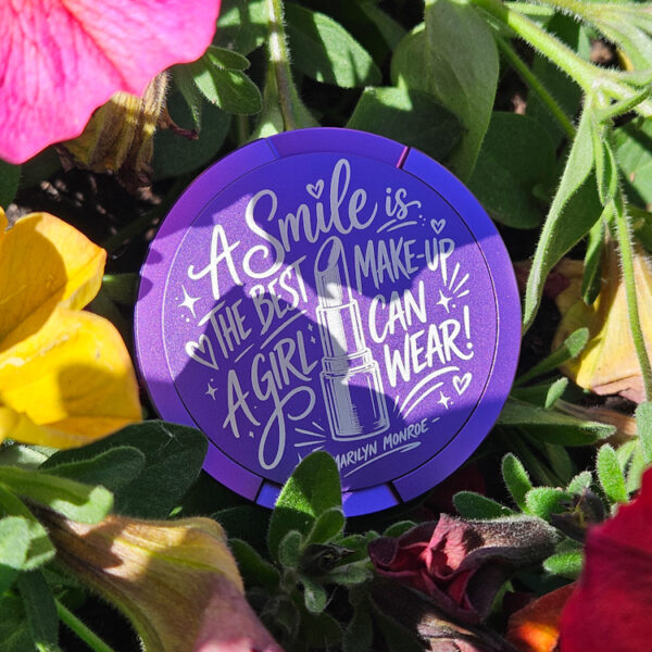 Lila snusdosa med citatet A Smile Is The Best Make-Up A Girl Can Wear